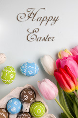 Painted easter eggs and bouquet of spring tulips closeup on a light blue background with space for congratulation