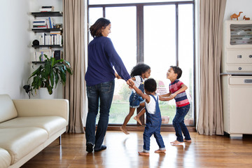Une mère et ses enfants font la ronde devant la fenêtre du salon