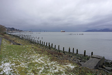 Fototapeta premium Astoria Megler bridge and a freighter on the Columbia river in Astoria Oregon on a gloomy wet and cold day
