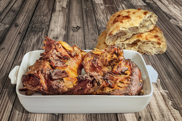 Roasted Lamb Shoulder in Porcelain Casserole with Pitta Bread Halves Set on Old Weathered Cracked Wooden Table Surface