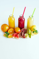 Freshly squeezed juice from citrus fruits in bottles on white background