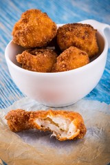 Few pieces of fried cauliflower on blue board with one tasted