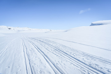 Clear sunny sky with skiing tracks in a winter landscape in snow covered mountains