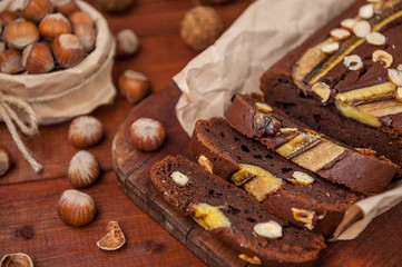 Chocolate cake with banana and hazelnut on a wooden background