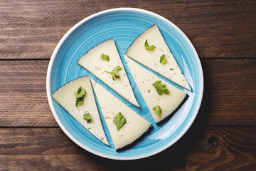 Close-up of a blue dish with cheese on rustic brown wooden table. Horizontal shoot.