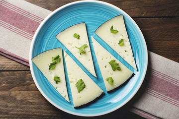 Cheese on a blue plate over a nice napkin and a brown amdera table. Horizontal shoot.
