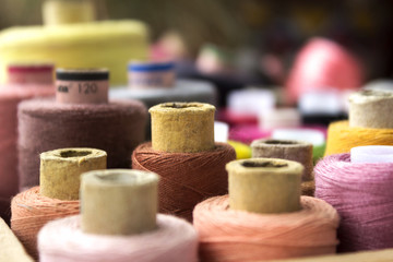 Fototapeta na wymiar Multicolored reel of thread for sewing, blurred spools, background