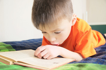children education, boy reading book lying on bed, child portrait with book, education concept, interesting storybook