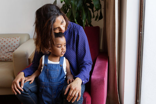 Une m&egrave;re et son jeune enfant font un c&acirc;lin sur un fauteuil pr&egrave;s de la fen&ecirc;tre