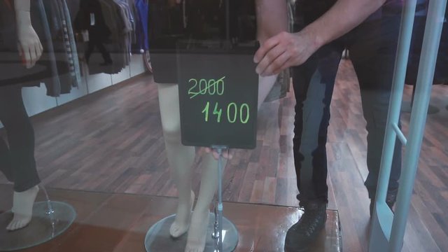 Shop assistant establishes the sign with information about discount