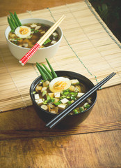 Asian miso soup in bowls on bamboo mat on table