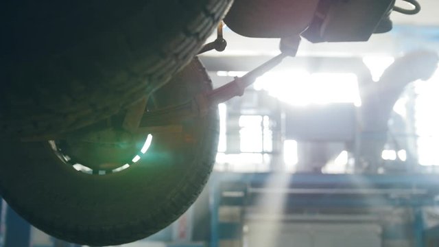 SUV Car lifted in automobile service for repairing, worker fixing faults
