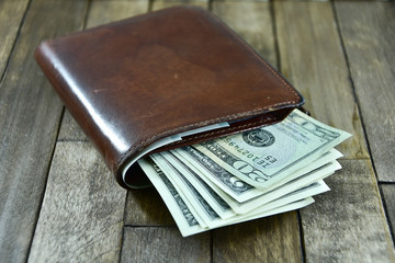brown men's wallet and dollars