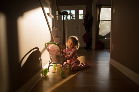 Girl playing with dolls pushchair in passageway