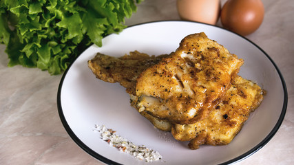 battered fish fried on a white plate with salad and salt and herbs de Provence