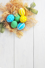 Easter eggs in the nest on rustic white background