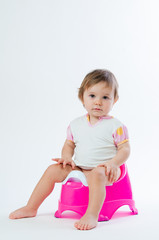 Little smiling girl sitting on a pot. Isolated on white background.