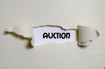 The word auction appearing behind torn paper