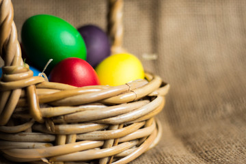 Colored Easter eggs in a basket on a rustic background