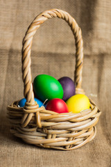 Colored Easter eggs in a basket on a rustic background