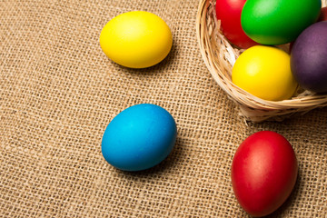 Colored Easter eggs in a basket on a rustic background