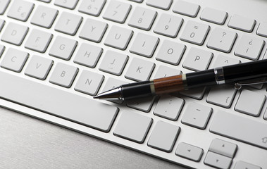 Ballpoint pen on a computer keyboard. Technology. Horizontal shoot.