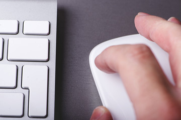 Hand on a mouse and next to a computer keyboard while surfing the internet. Technology.