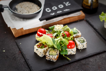 Vegetarian sushi roll on a stone plate and dark concrete background