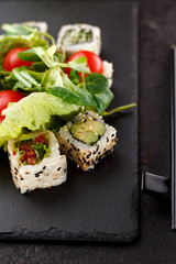 Vegetarian sushi roll on a stone plate and dark concrete background