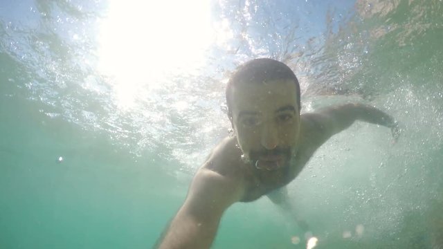 Man swimming and having fun in the water in summer. First person view of a young man underwater. Summer and relax concepts