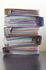 Five folders with documents stacked in a pile on the table