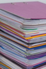 Several multicolored folders with documents stacked in a pile on