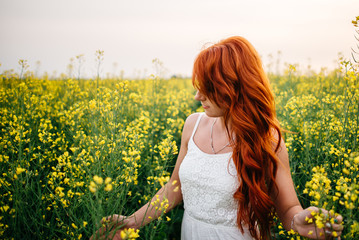 Young red-haired woman in a rapeseed field