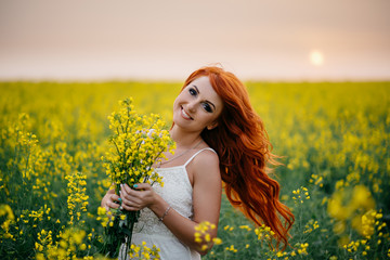 Naklejka na ściany i meble Young red-haired woman in a rapeseed field