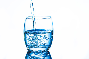 Water being poured into transparent glass. Splash bubbles inside the glass.