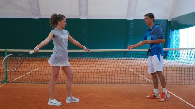 The coach works with the girl on tennis court