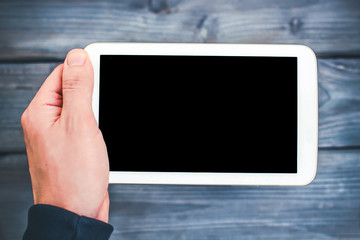 Holding white blank screen empty copy space tablet over blue wooden table.