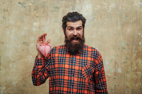Happy bearded man with beard holds rosy textile heart