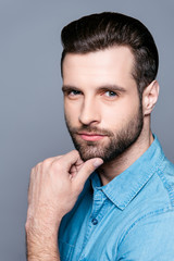 Fototapeta premium Vertical portrait of young handsome man isolated on gray background touching chin with his hand