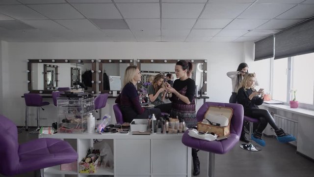 The camera moves in a spacious room where makeup artists hold master class for their permanent and wealthy clients. Beauty salon has a large number of beautiful purple chairs.
