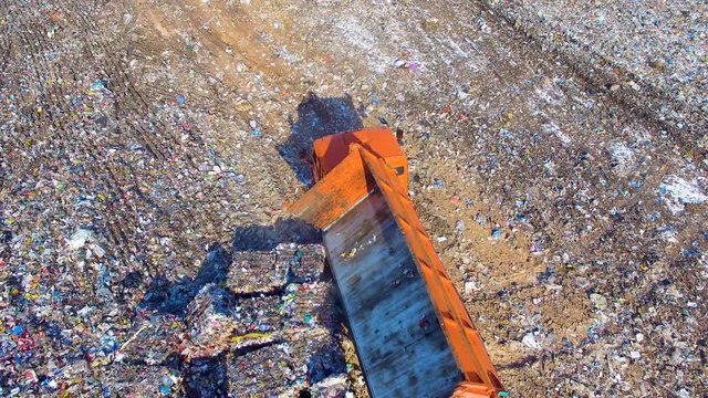 Truck unloading garbage, waste at landfill, junkyard. Aerial view 4K
