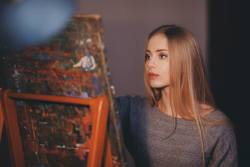 Artist beautiful girl paints a picture on canvas with watercolor in her workshop and art school.