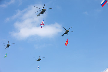 Helicopters in the blue sky are carrying Russian flags