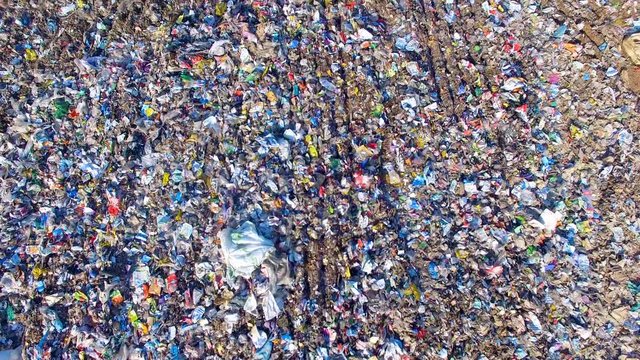 Piles of empty bottles, bags and other plastic in the garbage dump. Aerial. 4K.