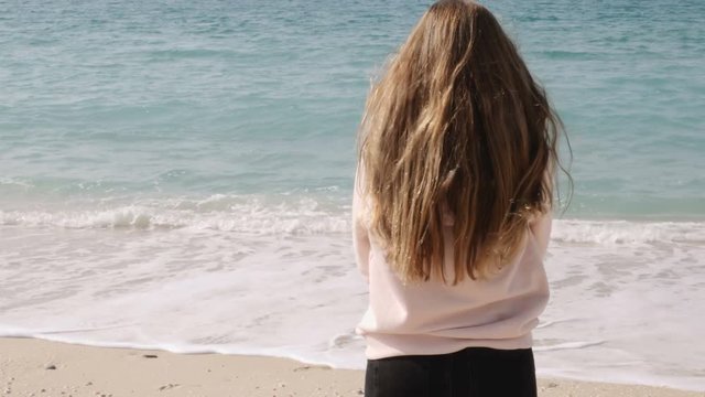 Girl with long ginger red hair enjoying sea breeze against background of seascape. Sea breeze playing with hair.