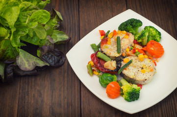 Fish fillet with mixed vegetables. Wooden background. Top view. Close-up