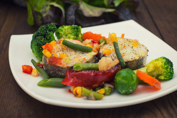 Fish fillet with mixed vegetables. Wooden background. Top view. Close-up