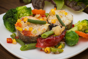 Fish fillet with mixed vegetables. Wooden background. Top view. Close-up