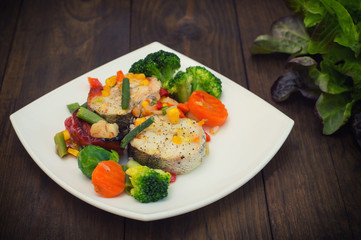 Fish fillet with mixed vegetables. Wooden background. Top view. Close-up
