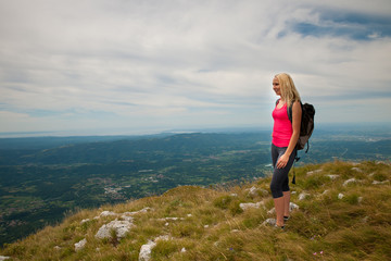 Naklejka na ściany i meble Trekking - woman hiking in mountains on a calm sumer day